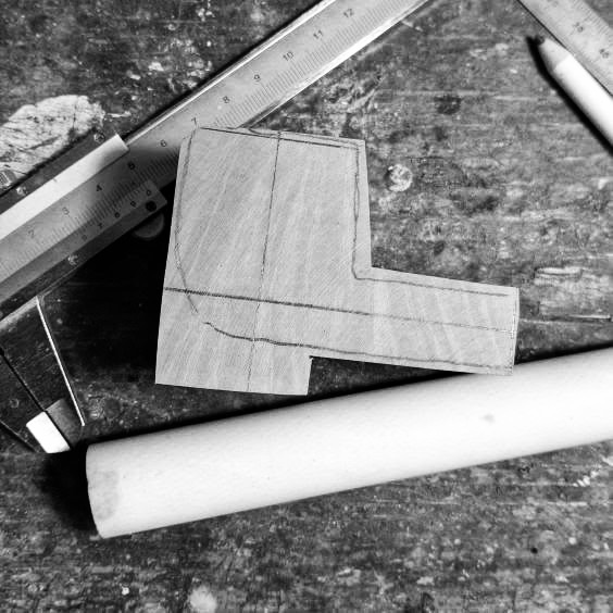 Auf Holz angezeichnete Pfeifenkontur mit Lineal und Messschieber auf der Werkbank, Schwarz-Weiß-Aufnahme