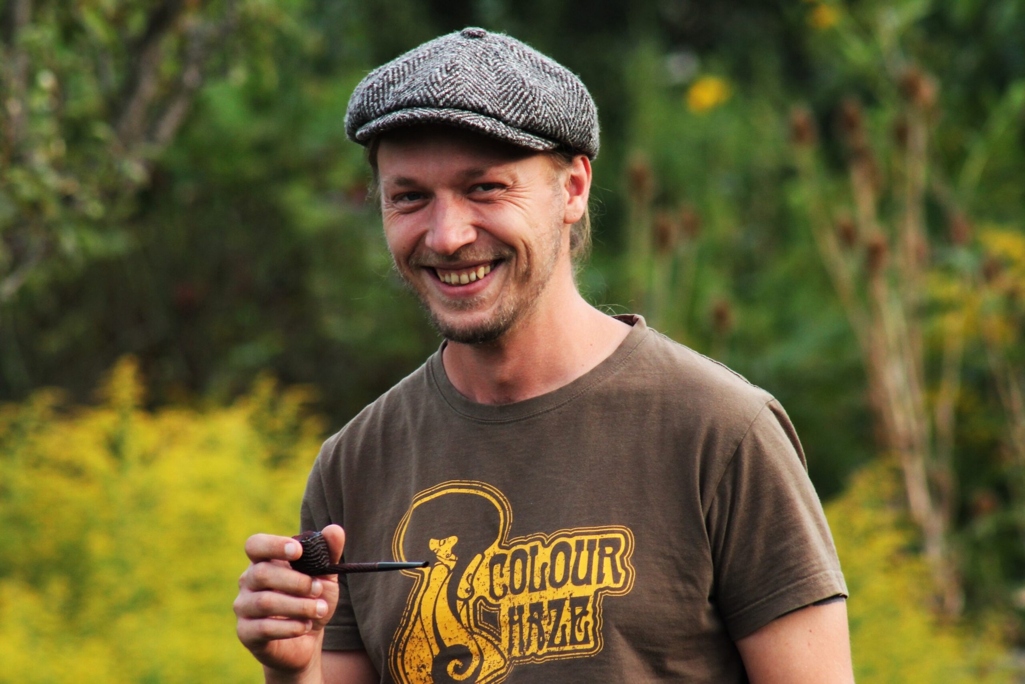Tobias Höse mit Schiebermütze, eine Pfeife in der Hand, im Garten