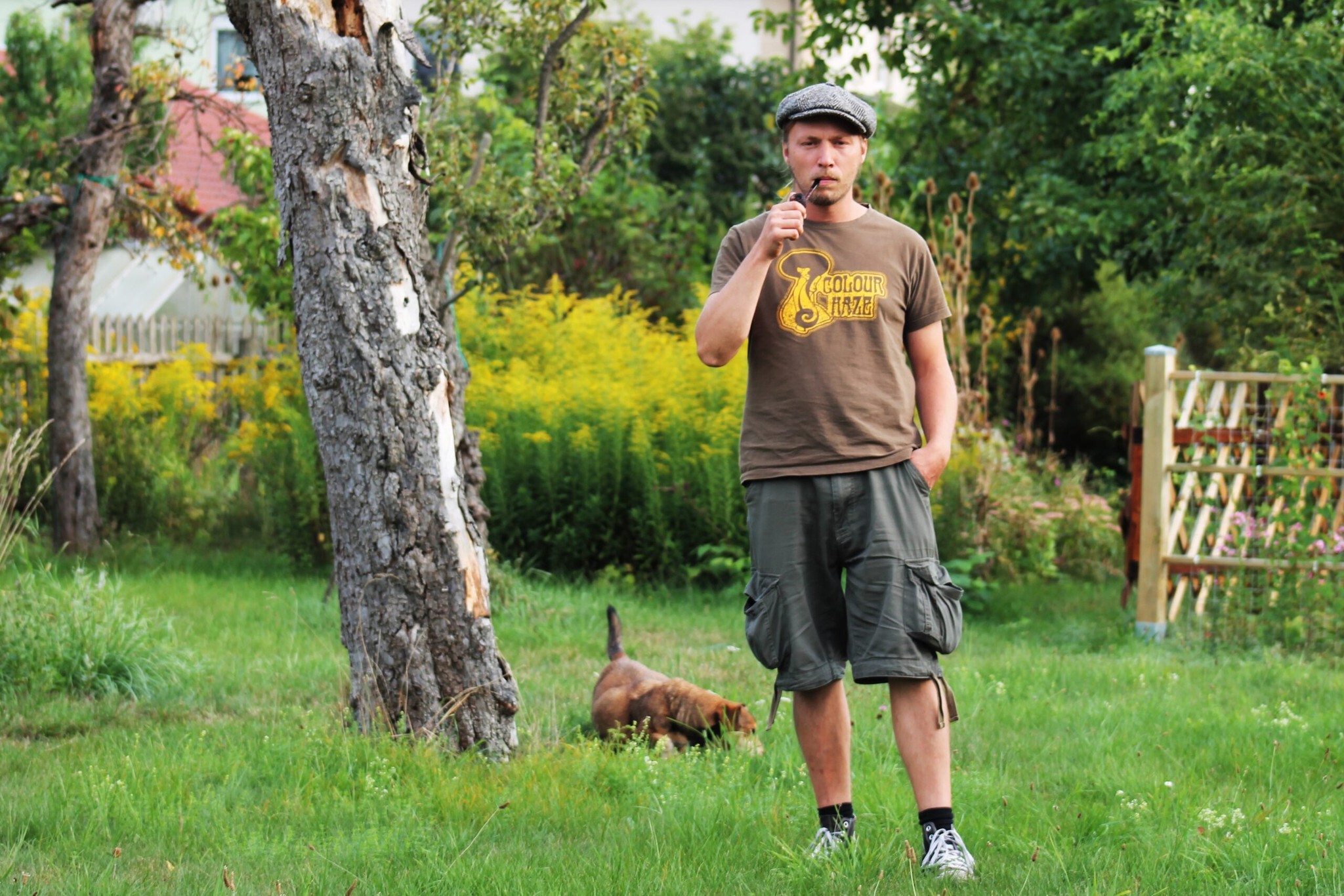Tobias Höse mit Pfeife im Garten, im Hintergrund ein Hund